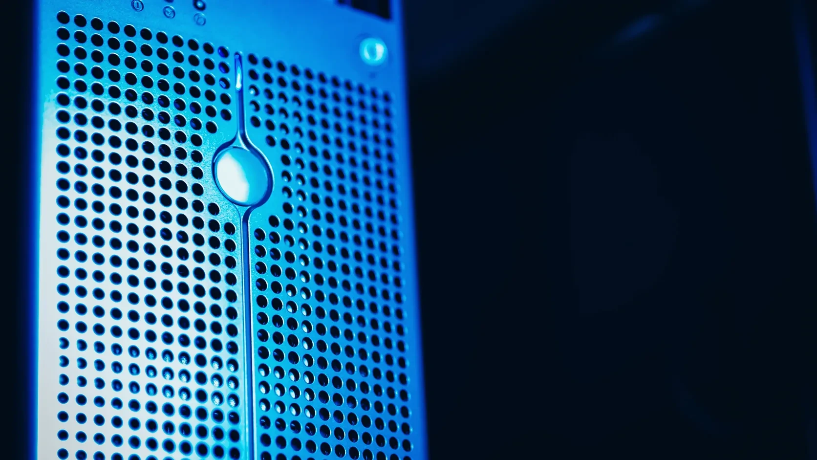 Close-up of a perforated blue-lit server unit in a dark data centre.